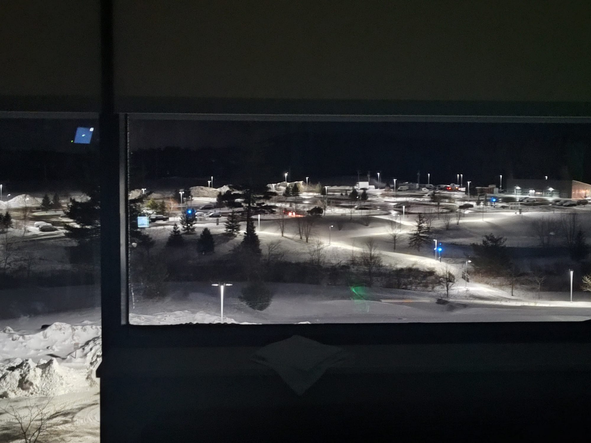 night sky, parking lot covered in lights and snow covered walking paths